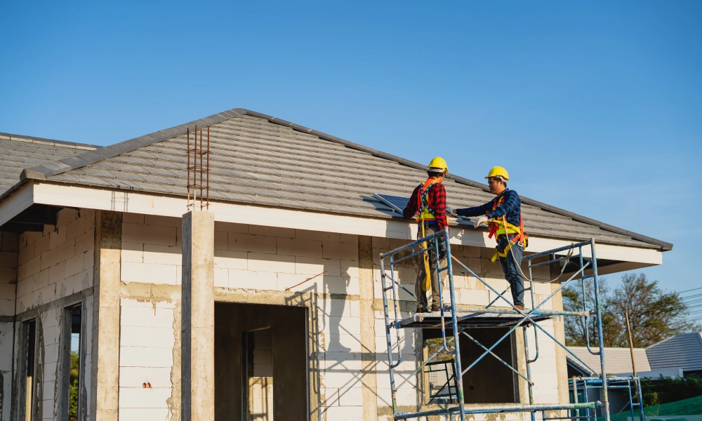 Two construction workers on a ladder working on the roof of a house