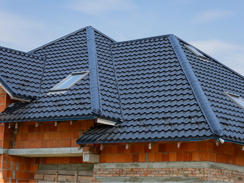 House with a slate roof and a brick wall, with a few wooden objects at the bottom
