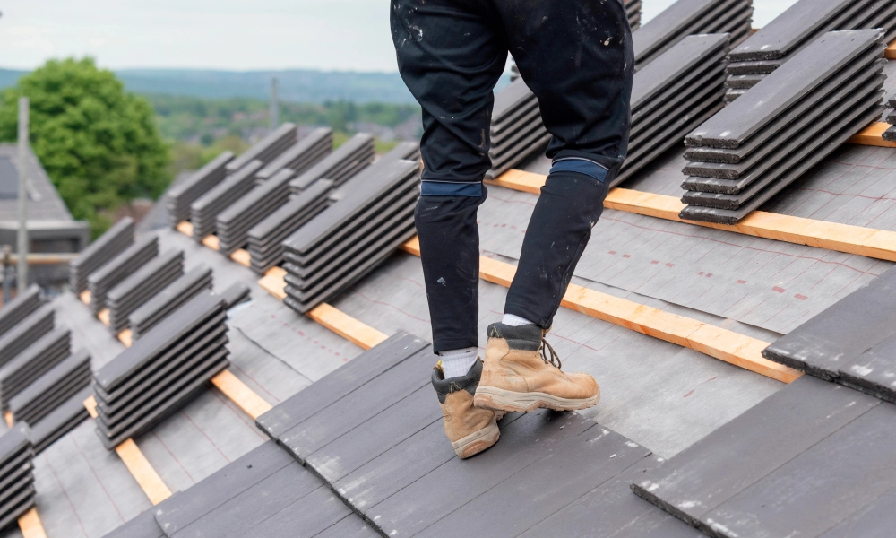 Man standing on top of a roof with a lot of metal sheets, surrounded by trees